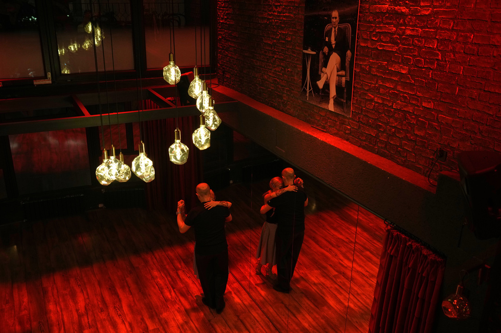 A couple dances tango next to a portrait of modern Turkey founder Mustafa Kemal Ataturk during a milonga evening at La Cumparsita in Istanbul, Turkey, Tuesday, Jan. 27, 2026. (AP Photo/Francisco Seco)