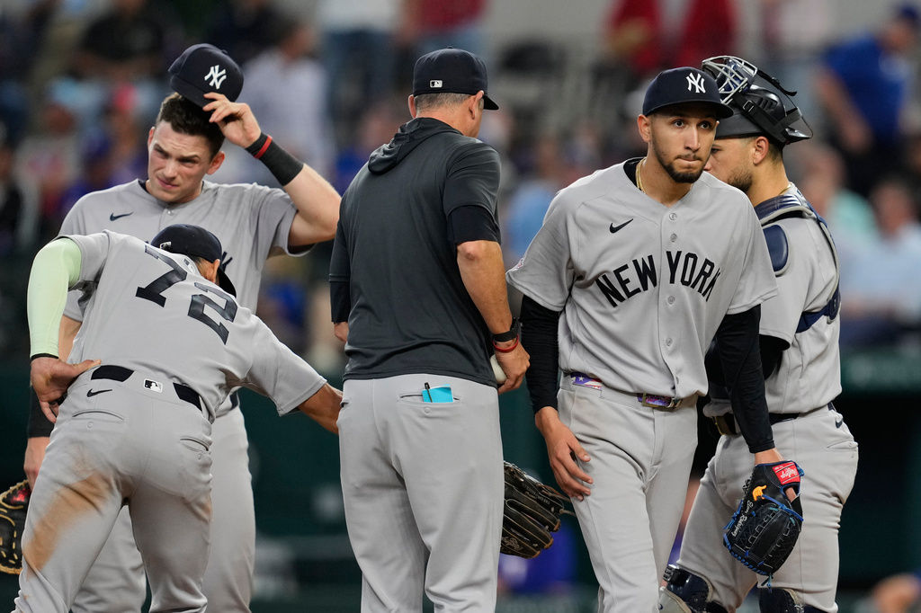 New York Yankees starting pitcher Elmer Rodriguez, right front, walks to the dugout after turning the ball over to manager Aaron Boone, center left, as José Caballero (72), Ben Rice, left rear, and J.C. Escarra, right rear, stand on the mound in the fifth inning of a baseball game against the Texas Rangers Wednesday, April 29, 2026, in Arlington, Texas. (AP Photo/Tony Gutierrez)