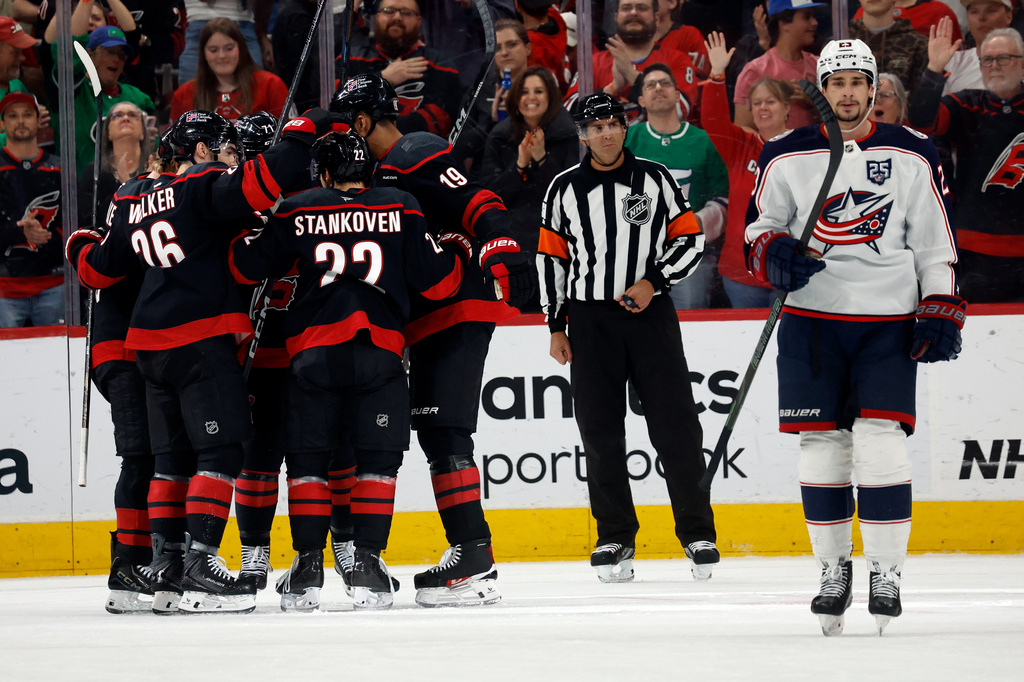 Carolina Hurricanes' Logan Stankoven (22) celebrates his goal with teammates as Columbus Blue Jackets' Sean Monahan (23) skates by during the first period of an NHL hockey game in Raleigh, N.C., Thursday, April 2, 2026. (AP Photo/Karl DeBlaker)