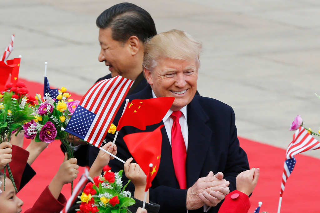 FILE - U.S. President Donald Trump, right, and Chinese President Xi Jinping are greeted by children waving flowers and flags during a welcome ceremony at the Great Hall of the People in Beijing, Nov. 9, 2017. (AP Photo/Andy Wong, File)