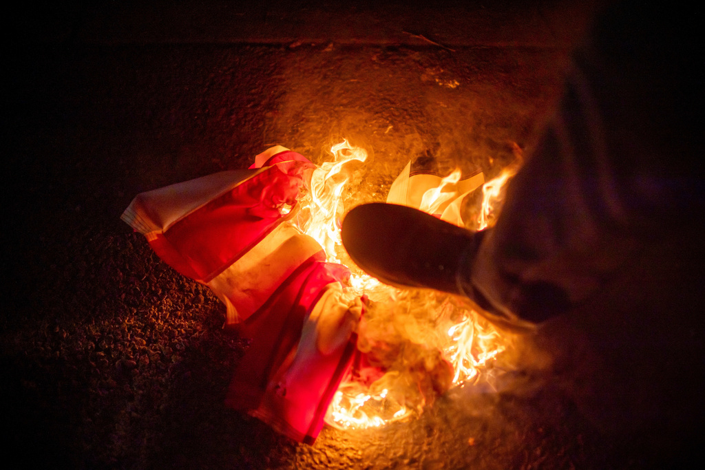 A protester stomps on a burning U.S. flag during a protest near a U.S. Immigration and Customs Enforcement facility in Portland, Ore., Monday, Oct. 6, 2025. (AP Photo/Ethan Swope)