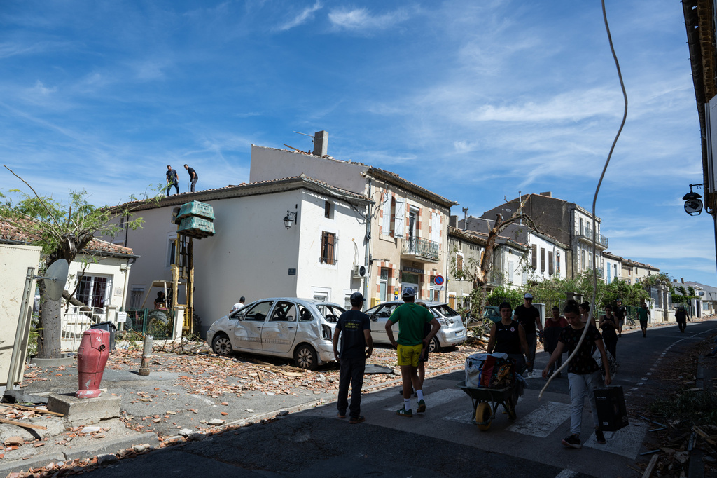 Resident watch damaged houses after a tornado ravaged the small village of Pomas in southern France, leaving dozens injured, Tuesday Aug. 25, 2026. (AP Photo/Frederic Lancelot)