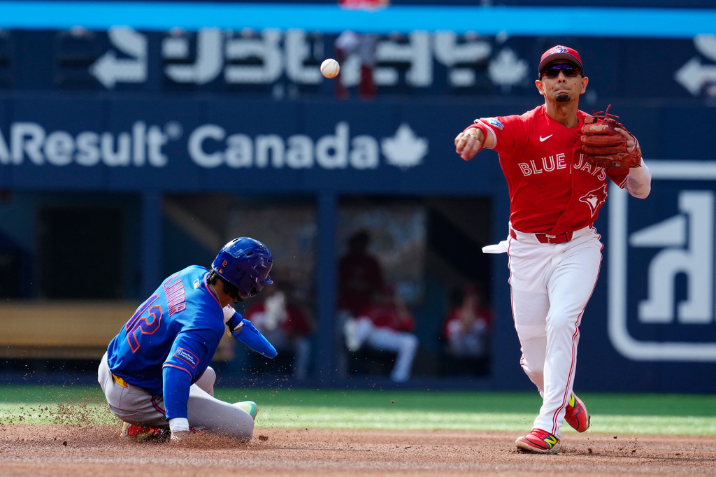 Blue Jays' Andres Gimenez tries to turn the double play but New York Mets' A.J Ewing is safe at first base during fourth inning MLB baseball action in Toronto on Wednesday, July 1, 2026. (Frank Gunn/The Canadian Press via AP)