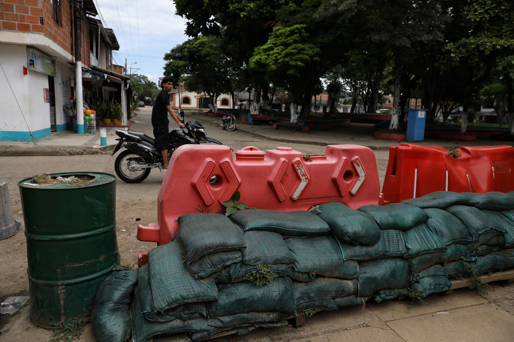 A man rides his motorcycle past a barricade blocking streets in Potrerito, Colombia, Tuesday, May 19, 2026, following attacks by dissidents of the former Revolutionary Armed Forces of Colombia, or FARC. (AP Photo/Santiago Saldarriaga)