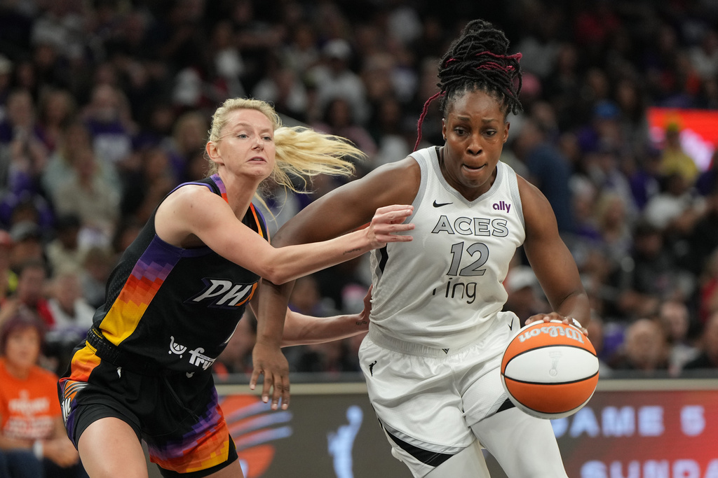 Las Vegas Aces guard Chelsea Gray (12) drives past Phoenix Mercury guard Lexi Held, left, during the first half of Game 4 of the WNBA basketball finals, Friday, Oct. 10, 2025, in Phoenix. (AP Photo/Rick Scuteri)