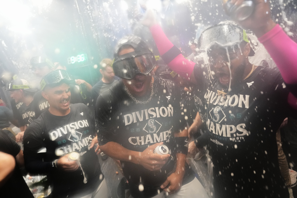 Seattle Mariners center fielder Julio Rodriguez, center, and right fielder Victor Robles, right, celebrate after the team's win against the Colorado Rockies to clinch the American League West Division, Wednesday, Sept. 24, 2025, in Seattle. (AP Photo/Ryan Sun)