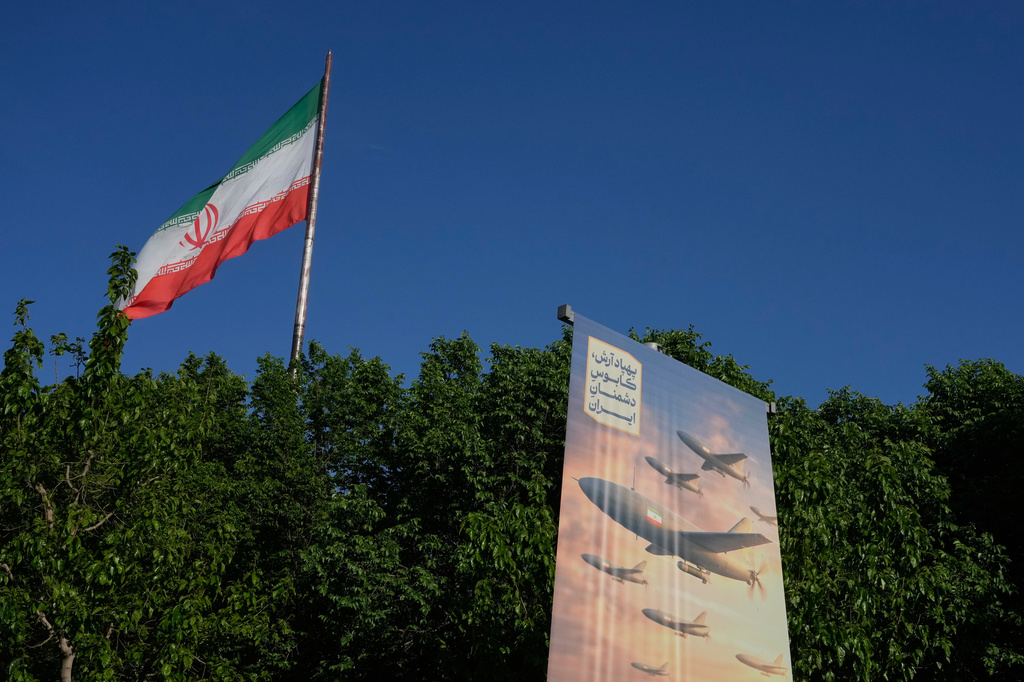 A banner shows a graphic depicting Iranian-built drones with a sign in Farsi that reads: "Arash drone is the nightmare for Iran's enemies," as an Iranian flag waves at left, in Tehran, Iran, Tuesday, April 21, 2026. (AP Photo/Vahid Salemi)