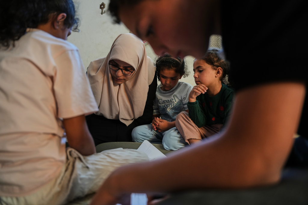 Ikhlas al-Kafarna, 35, teaches her orphaned nieces and nephews at her home in Gaza City, May 31, 2026. The children lost their parents in an Israeli airstrike. (AP Photo/Abdel Kareem Hana)