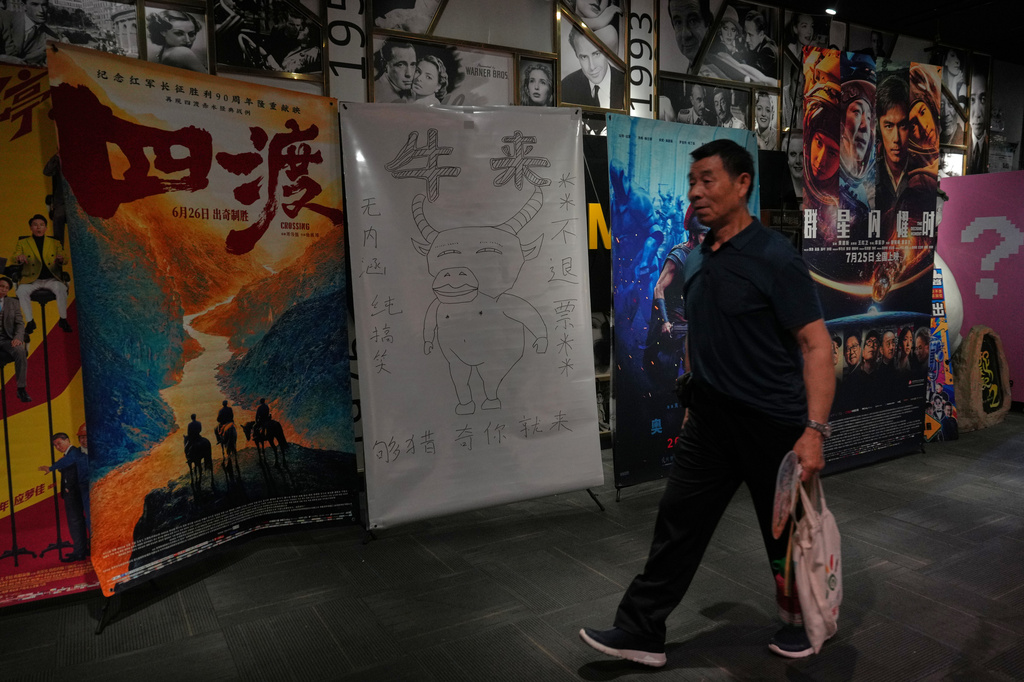 A man walks by a drawing poster promoting a Chinese animated film "Niu Lai" on display with other movie posters at a cinema in Beijing, Tuesday, Aug. 18, 2026. (AP Photo/Andy Wong)