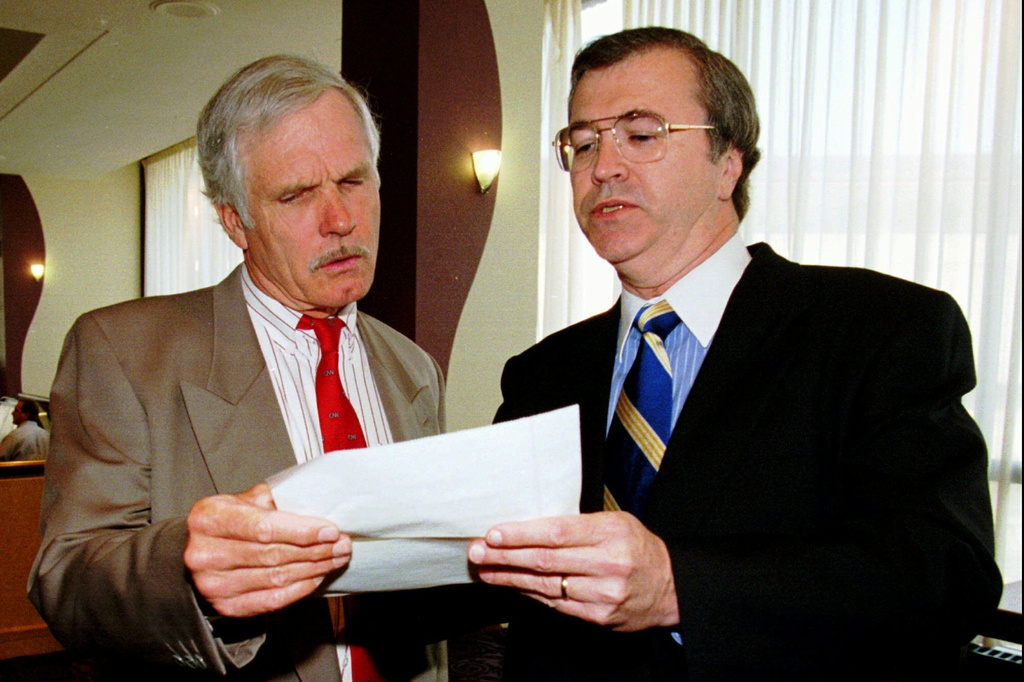 FILE - Turner Broadcasting System Chairman Ted Turner, left, stops to talk with CNN President Tom Johnson before going into a shareholders meeting in Atlanta on June 7, 1996. (AP Photo/Ric Feld, File)