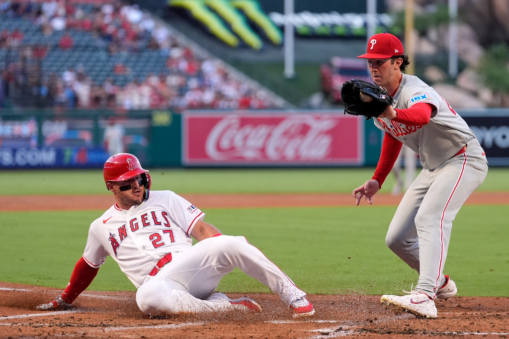 Los Angeles Angels' Mike Trout, left, scores on wild pitch by Philadelphia Phillies starting pitcher Andrew Painter, left, as Painter takes a late throw during the first inning of a baseball game Friday, Aug. 28, 2026, in Anaheim, Calif. (AP Photo/Mark J. Terrill)