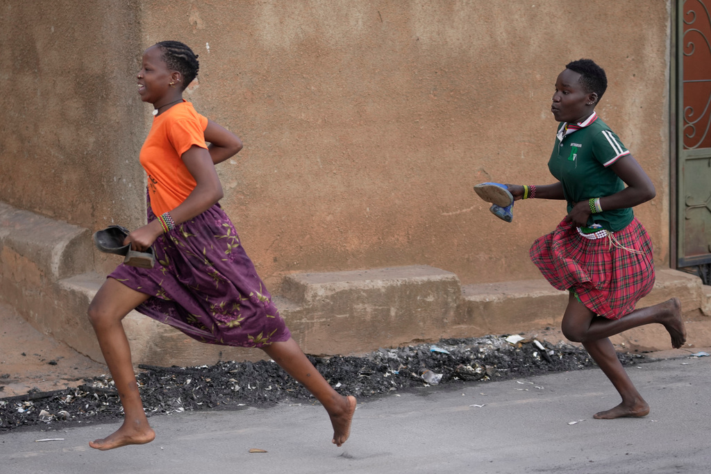 Girls run during protests following the preliminary results in Kampala, Uganda, Friday, Jan. 16, 2026. (AP Photo/Brian Inganga)
