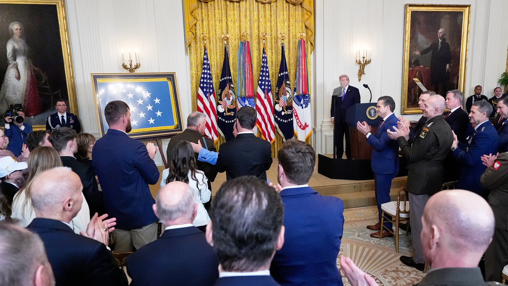 President Donald Trump looks on during a standing ovation for Sergeant Major Terry P. Richardson, U.S. Army (retired), center with hand on his back, during a Medal of Honor ceremony in the East Room of the White House, Monday, March 2, 2026, in Washington. (AP Photo/Alex Brandon)