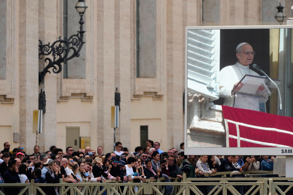 Faithful stand in St. Peter's Square at the Vatican near a giant monitor broaccasting Pope Leo XIV as he appears at his studio window for the traditional Sunday blessing, Sunday, March 8, 2026. (AP Photo/Gregorio Borgia)