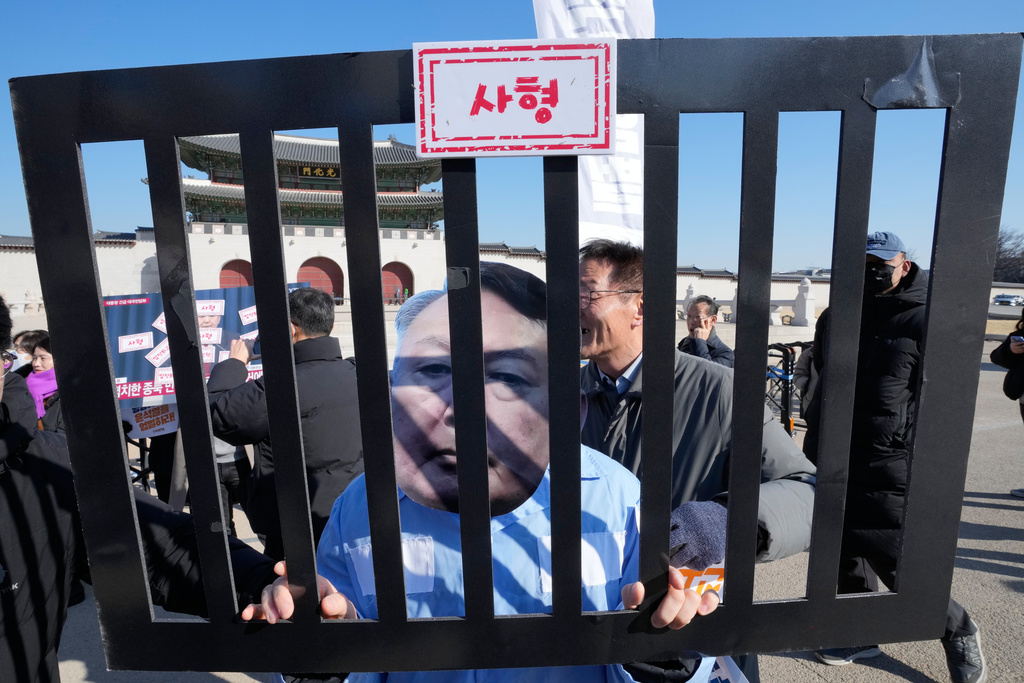 A protester wearing a mask of South Korean former President Yoon Suk Yeol attends a press conference demanding death sentence for Yoon ahead of the court's verdict in Seoul, South Korea, Thursday, Feb. 19, 2026. The sign at top reads, "Death." (AP Photo/Ahn Young-joon)
