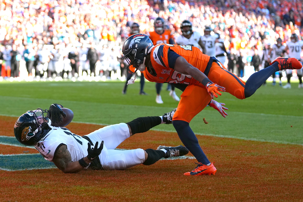 Jacksonville Jaguars wide receiver Parker Washington (11) scores a touchdown against Denver Broncos cornerback Ja'Quan McMillian, right, during the first half of an NFL football game in Denver, Sunday, Dec. 21, 2025. (AP Photo/Jack Dempsey)