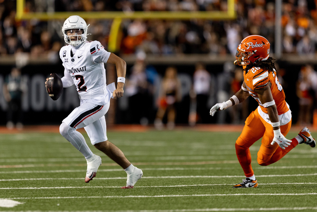 Cincinnati quarterback Brendan Sorsby (2) carries the ball past Oklahoma State linebacker Jacobi Oliphant Jr., right, in the first half of an NCAA college football game Saturday, Oct. 18, 2025, in Stillwater, Okla. (AP Photo/Mitch Alcala)