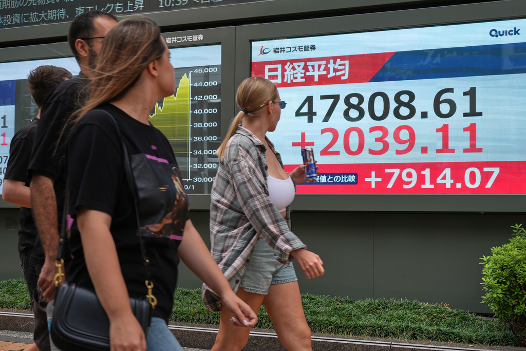 People walk in front of an electronic stock board showing Japan's Nikkei index at a securities firm Monday, Oct. 6, 2025, in Tokyo. (AP Photo/Eugene Hoshiko)