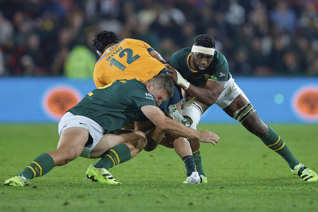 South Africa's captain Siya Kolisi, right, with his teammate tackles Australia's Len Ikitau, centre, during a rugby championship test match between South Africa and Australia, at Ellis Park stadium in Johannesburg, South Africa, Saturday, Aug. 16, 2025. (AP Photo/Frans Lombard)