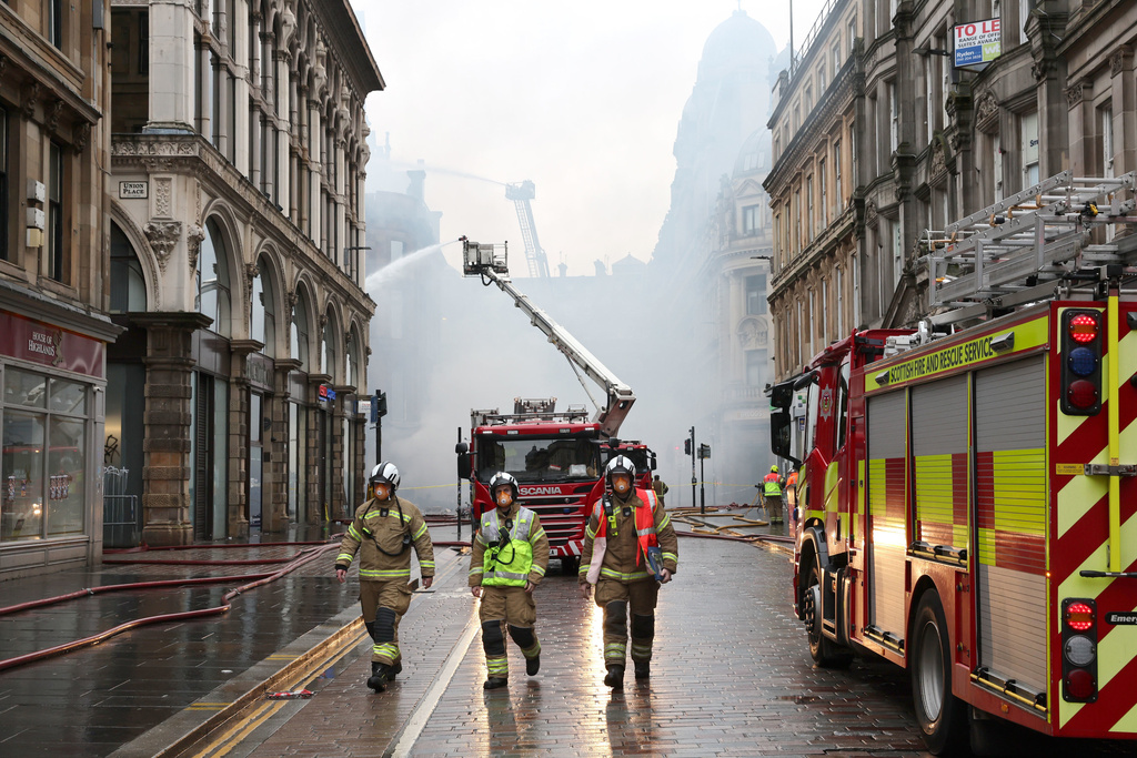 Firefighters damp down the remains of a fire which broke out in a building adjacent to Glasgow Central railway station on Sunday, in Glasgow, Scotland, Monday March 9, 2026. (Robert Perry/PA via AP)