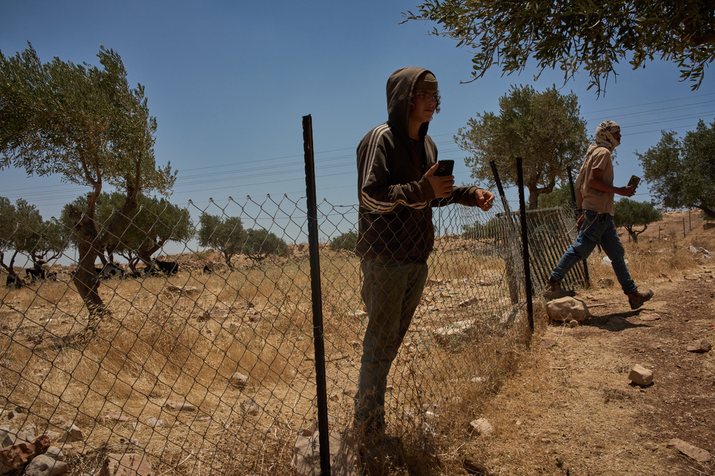 An Israeli settler steps into the courtyard of a home as another stands next to the fence, trespassing on Palestinian property on the outskirts of the West Bank town of Taybeh, Thursday, June 25, 2026. (AP Photo/Leo Correa)