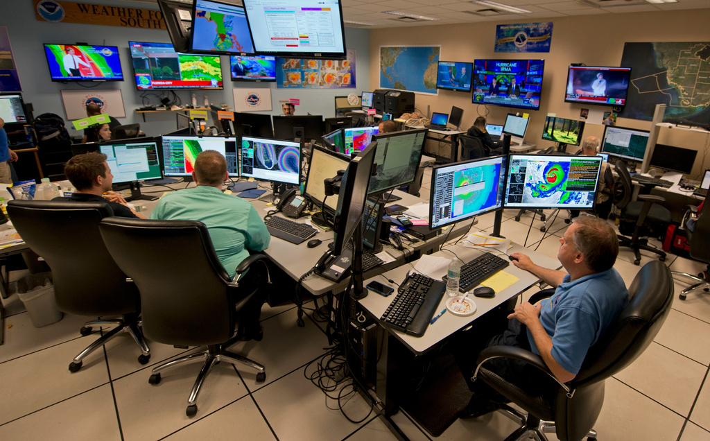FILE - Forecasters at the National Weather Service office monitor Hurricane Irma, Sept. 9, 2017, at the hurricane center in Miami. (AP Photo/Andy Newman, File)