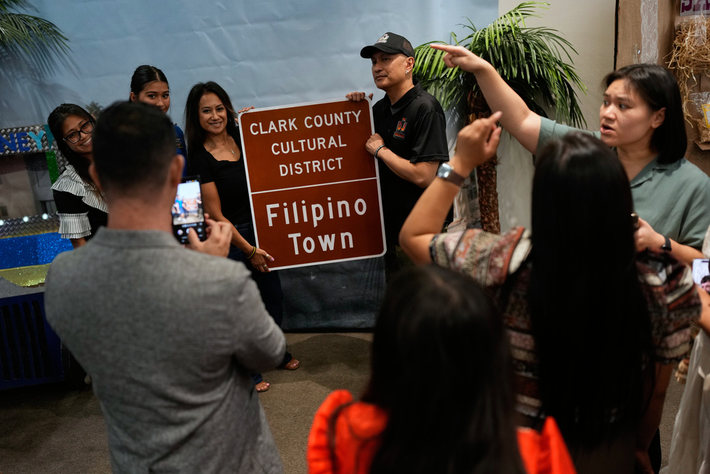 People pose around a sign at a celebration for the designation of Filipino Town as a Clark County Cultural District, Thursday, Oct. 9, 2025, in Las Vegas. (AP Photo/John Locher)