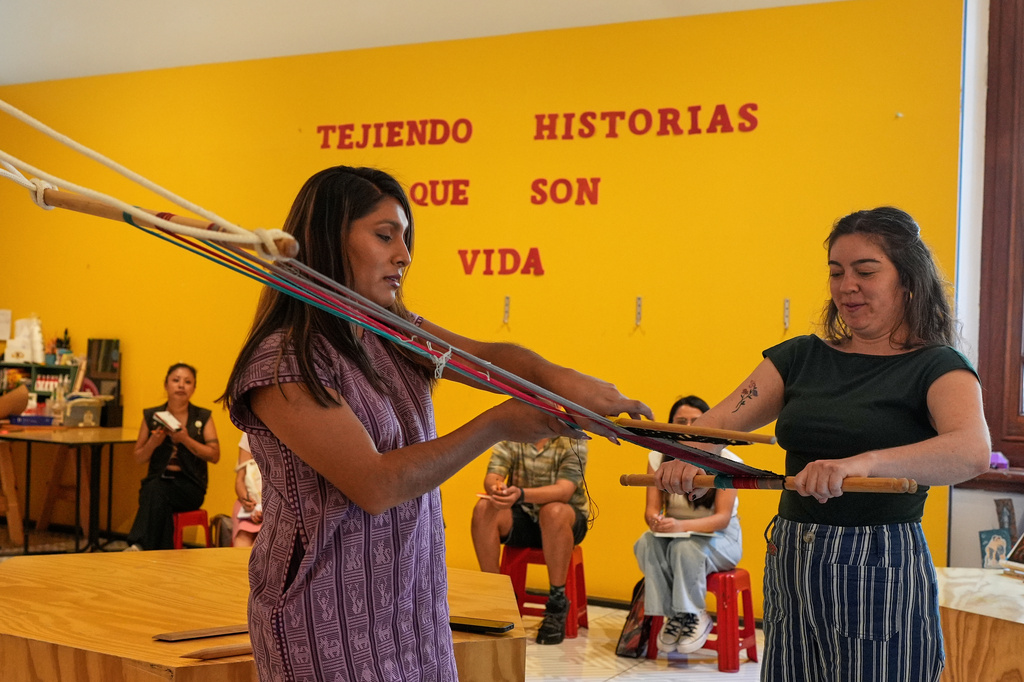 Muxe artist Xaneri Merino, left, gives a backstrap loom workshop for LGBTQ+ people in Mexico City, Tuesday, April 14, 2026. (AP Photo/Marco Ugarte)