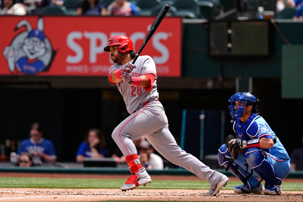 Cincinnati Reds' Eugenio Suarez (28) follows through on a run-scoring single as Texas Rangers' Kyle Higashioka (11) looks on in the fourth inning of a baseball game Sunday, April 5, 2026, in Arlington, Texas. (AP Photo/Tony Gutierrez)