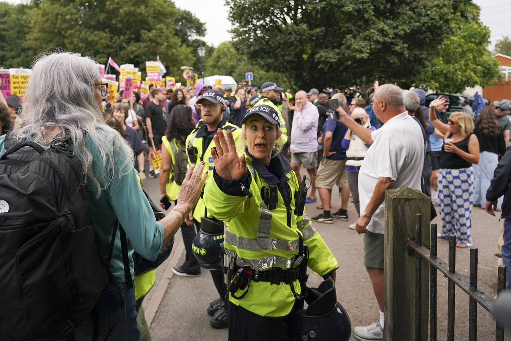 FILE - A police officer reacts as demonstrators hold placards and banners as they leave a protest outside the Bell Hotel in Epping, near London, Sunday, July 27, 2025.(AP Photo/Alberto Pezzali, file)