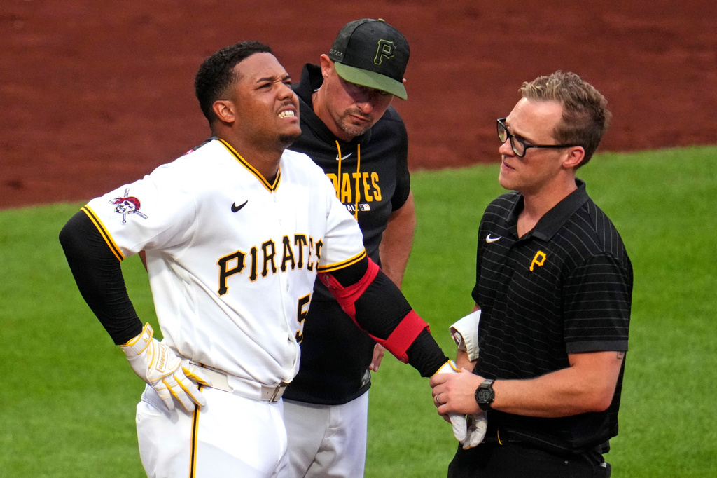 Pittsburgh Pirates manager Don Kelly, center, watches as Esmerlyn Valdez, left, is examined by a team trainer, right, after being hit by a pitch from Arizona Diamondbacks' Merrill Kelly during the fourth inning of a baseball game in Pittsburgh, Monday, July 27, 2026. (AP Photo/Gene J. Puskar)