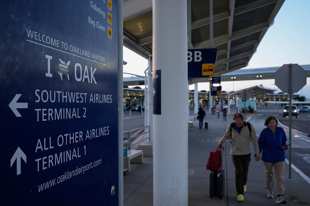 FILE - Travelers walk toward the entrance of Oakland's international airport Nov. 13, 2024, in Oakland, Calif. (AP Photo/Godofredo A. Vásquez, File)