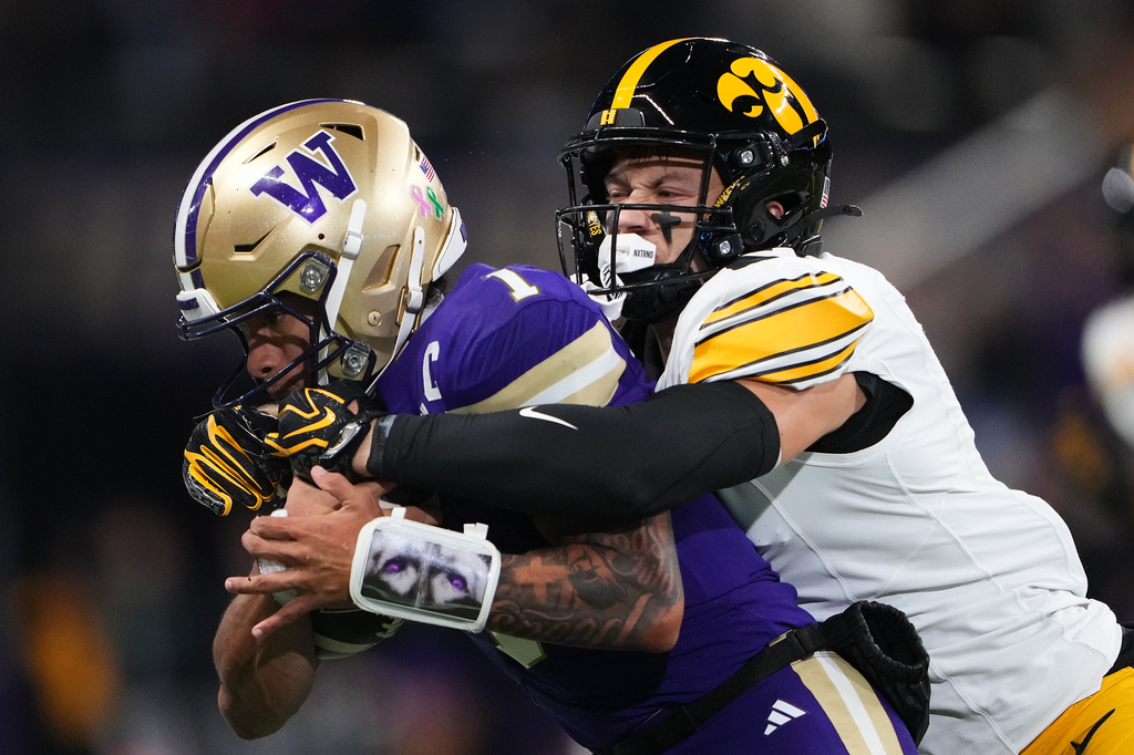 Iowa defensive back Zach Lutmer, right, tackled Washington quarterback Demond Williams Jr. during the first half of an NCAA college football game, Friday, Oct. 9, 2026, in Seattle. (AP Photo/Lindsey Wasson)