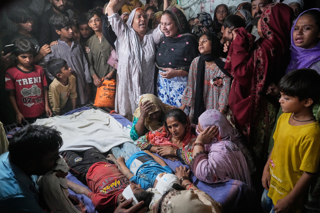 Women mourn next to the bodies of their children killed after the roof of a tutoring center under-construction collapsed, on the outskirts of Lahore, Pakistan, Tuesday, June 30, 2026. (AP Photo/K.M Chaudary)