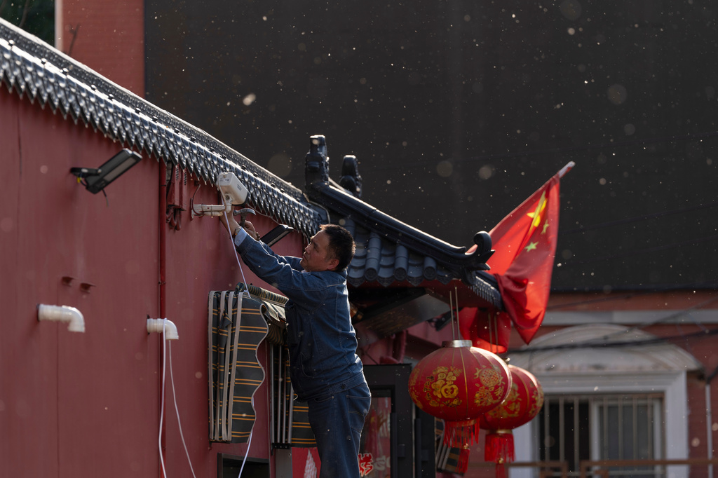 A man sets up a surveillance camera outside a restaurant with a Chinese national flag in Beijing, Friday, May 8, 2026. (AP Photo/Ng Han Guan)