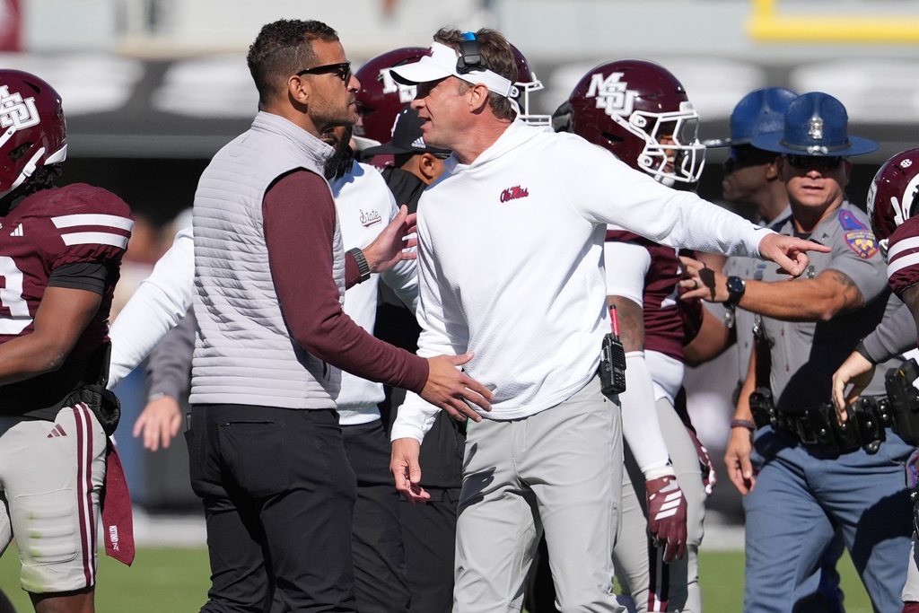 Mississippi head coach Lane Kiffin, right, and Mississippi State director of athletics Zac Selmon, left, confer during a scuffle between the teams in the first half of an NCAA college football game Friday, Nov. 28, 2025, in Starkville, Miss. (AP Photo/Rogelio V. Solis)