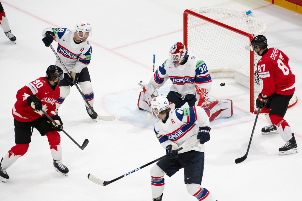 Canada's Ryan O'Reilly, left, scores the 4-4 against Norway's goaltender Tobias Normann, top center, Norway's Christian Kaasastul, top left, Norway's Max Krogdahl, bottom center, next to Canada's Sidney Crosby, right, during the 2026 IIHF Men's Ice Hockey World Championship preliminary round group B game between Canada and Norway, in Fribourg, Switzerland, Thursday, May 21, 2026. (Anthony Anex/Keystone via AP)