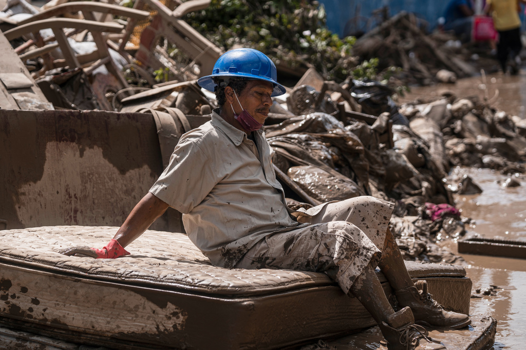 A man who cleaning flooded homes takes a break in Poza Rica, Veracruz state, Mexico, Sunday, Oct. 12, 2025. (AP Photo/Felix Marquez)