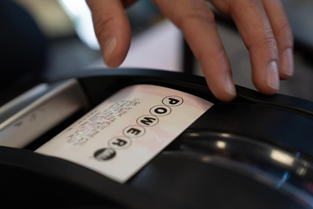 A convenience store employee grabs a Powerball lottery ticket for a customer on Monday, Dec. 22, 2025, in Portland, Ore. (AP Photo/Jenny Kane)