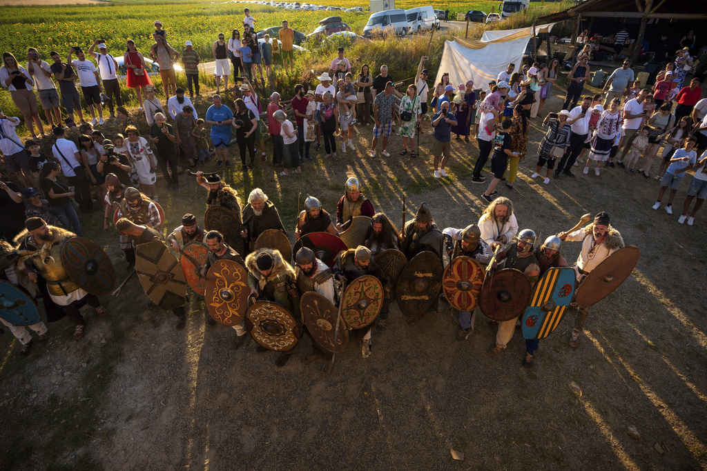 People watch as members of historical reenactment groups wearing Dacian warrior and Roman soldiers outfits, clash in Poiana, Romania, Sunday, July 13, 2025, during the Getodava historical reenactment festival. (AP Photo/Andreea Alexandru)