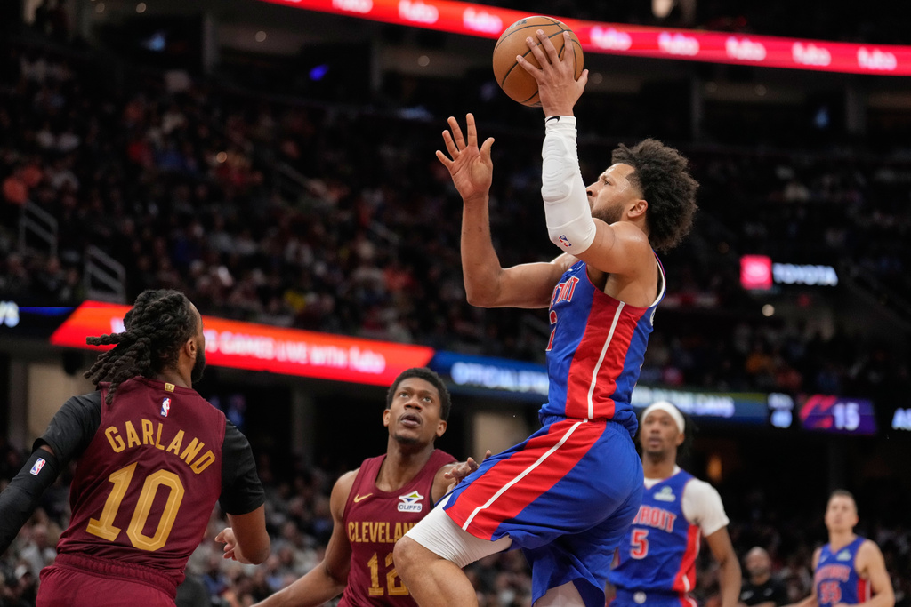 Detroit Pistons guard Cade Cunningham shoots between Cleveland Cavaliers guard Darius Garland (10) and forward De'andre Hunter (12) in the second half of an NBA basketball game Sunday, Jan. 4, 2026, in Cleveland. (AP Photo/Sue Ogrocki)
