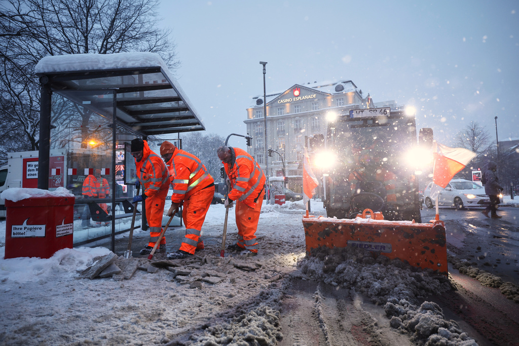 Hamburg municipal workers clear ice and snow from a bus stop at Stephansplatz, in Hamburg, Germany, Friday, Jan. 9, 2026. (Christian Charisius/dpa via AP)