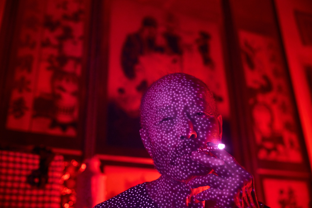 Yang Guoliang, who has been under surveillance by Chinese officials after complaining about a land dispute to the central government in Beijing, is illuminated by cellphone infrared facial recognition beams as he smokes a cigarette inside his home in Changzhou in eastern China's Jiangsu Province, Sept. 7, 2025. (AP Photo/Ng Han Guan)