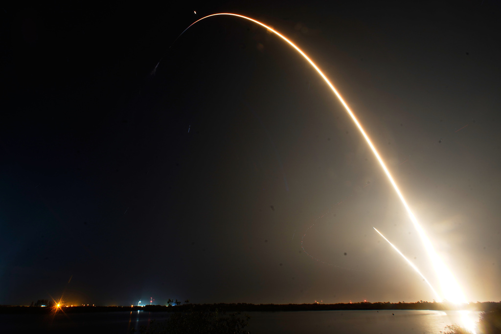 A SpaceX Falcon 9 rocket with a crew of four aboard the Dragon space craft is seen during a time exposure as it lifts off from pad 40 at the Cape Canaveral Space Force Station in Cape Canaveral, Fla., Friday, Feb. 13, 2026, as a second streak just to the left is the booster on a return landing at the launch pad. (AP Photo/John Raoux)