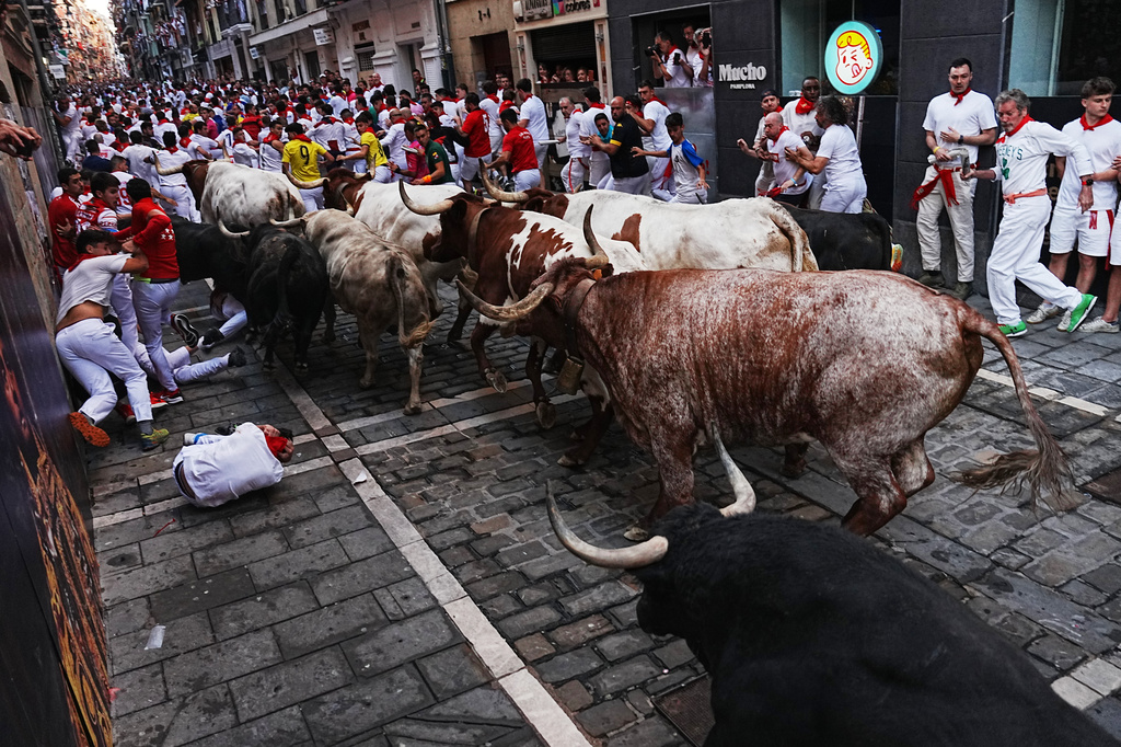 Revelers run alongside Fuente Ymbro's fighting bulls during the first running of the bulls at the San Fermín festival in Pamplona, Spain, Tuesday, July 7, 2026. (AP Photo/Miguel Oses)