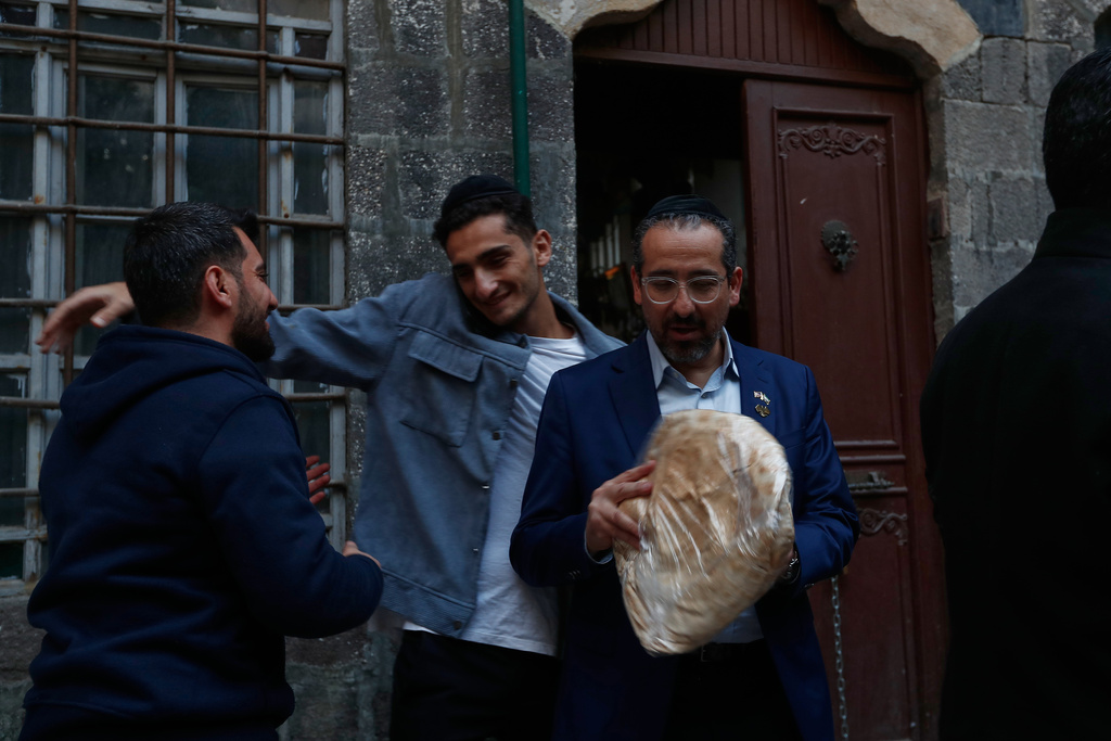 Syrian-American Jews, Joseph Hamra centre, and his father Henry, right, who is one of the founders of a new Jewish heritage initiative, stand outside at al-Firenj Synagogue in the old city of Damascus, Syria, Wednesday, Dec. 10, 2025.(AP Photo/Omar Sanadiki)