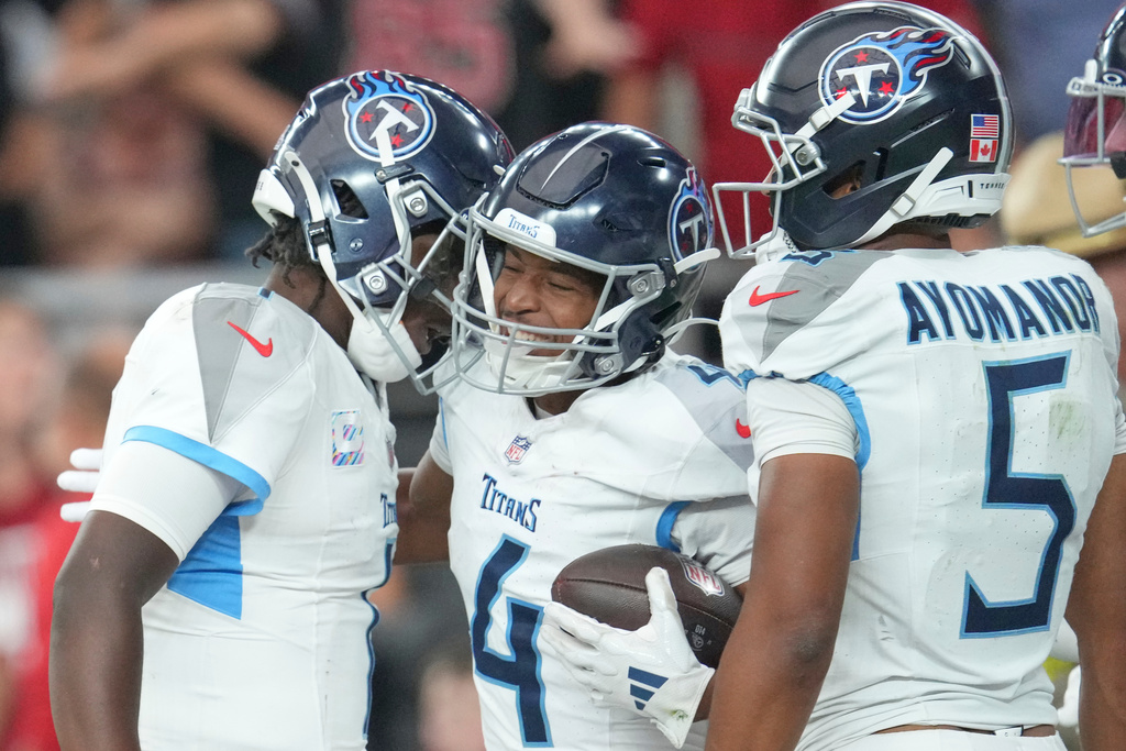 Tennessee Titans wide receiver Tyler Lockett (4) celebrates his touchdown with quarterback Cam Ward, left, and Elic Ayomanor (5) during the second half of an NFL football game Sunday, Oct. 5, 2025, in Glendale, Ariz. (AP Photo/Ross D. Franklin)