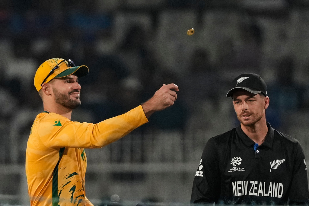 South Africa's captain Aiden Markram tosses the coin for toss as New Zealand's captain Mitchel Santner watches at the start of the first T20 World Cup cricket semifinal match between New Zealand and South Africa in Kolkata, India, Wednesday, March 4, 2026. (AP Photo/Anupam Nath)