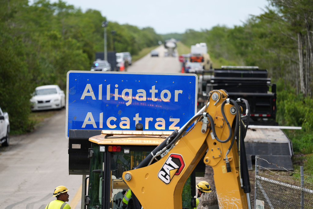 FILE - A loader holds a sign reading "Alligator Alcatraz" in its bucket as workers install it at the entrance to a new migrant detention facility at Dade-Collier Training and Transition facility, July 3, 2025, in Ochopee, Fla. (AP Photo/Rebecca Blackwell)