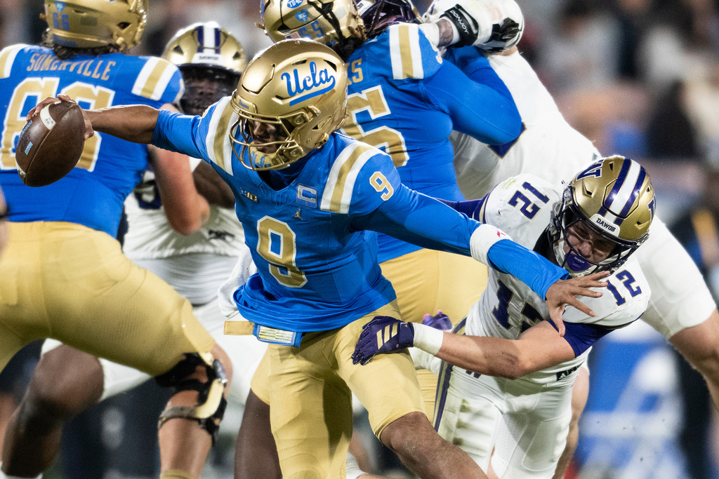 Washington safety Alex McLaughlin (12) tackles UCLA quarterback Nico Iamaleava (9) during the first half of an NCAA college football game, Saturday, Nov. 22, 2025, in Pasadena, Calif. (AP Photo/Kyusung Gong)